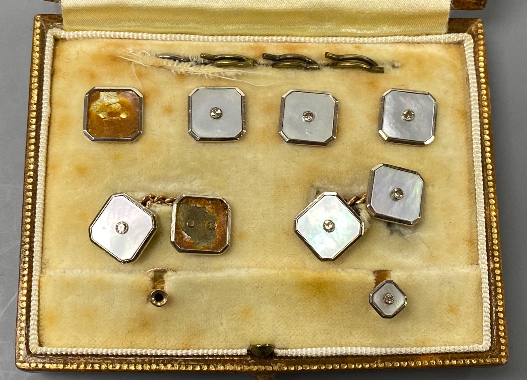 An early to mid 20th century part set of 18ct & 9ct, mother of pearl and diamond set octagonal dress stud set (a.f.), in fitted gilt tooled leather case.